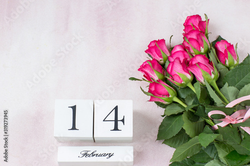 a bouquet of pink roses and the date of February 14 on cubes