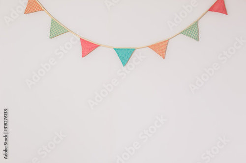 Garland of cute party flags hanging on the wall. Background with copyspace symbolising home celebration, birthday or festive mood