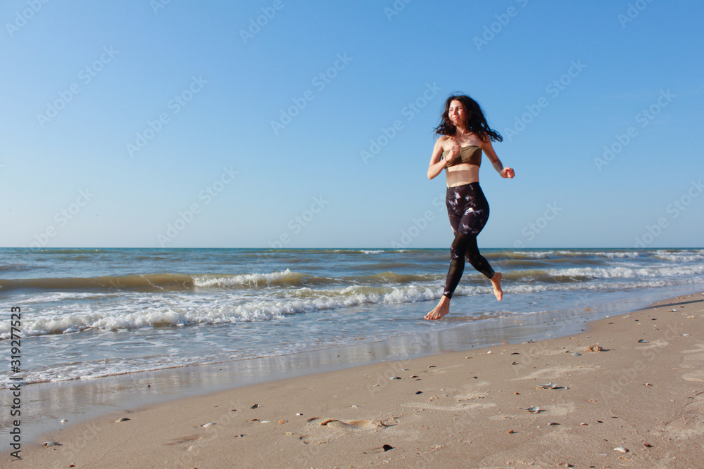 Sporty girl training outside. She is running by seaside. Athletic Fitness Woman Running on the Beach. Female Runner Jogging. Outdoor Workout. Fitness Concept. Morning workout and sport activity Sporty girl training outside. She is running by seaside. Athletic Fitness Woman Running on the Beach. Female Runner Jogging. Outdoor Workout. Fitness Concept. Morning workout and sport activity