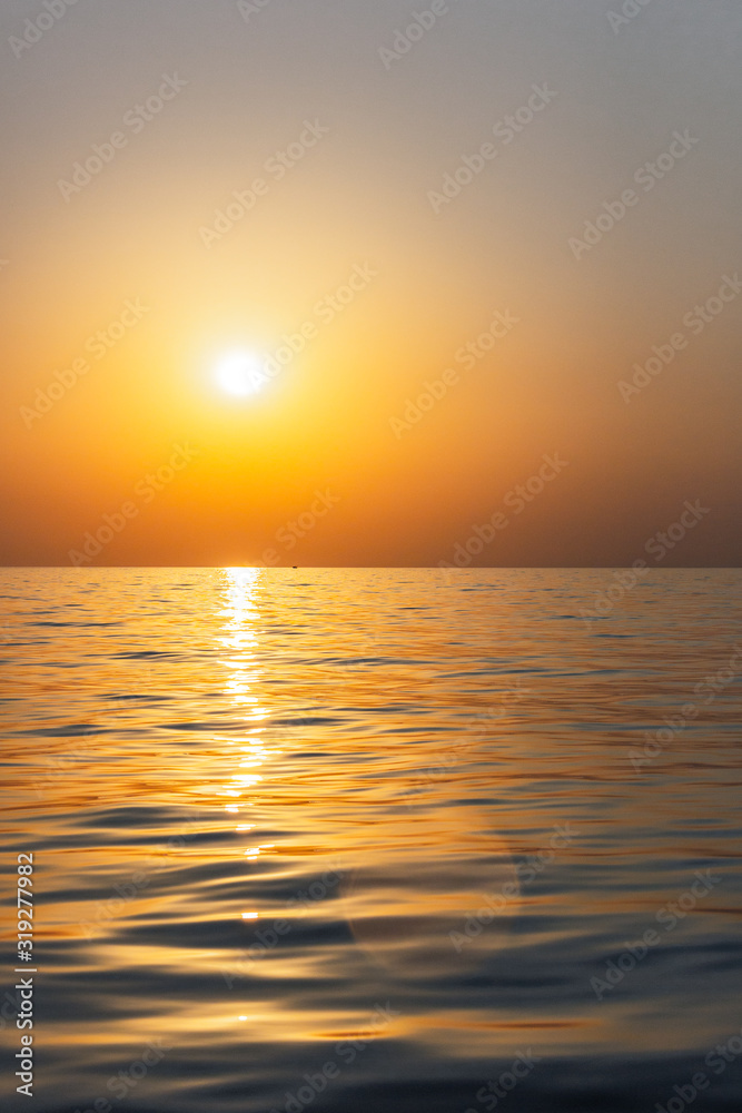 Naklejka premium Bright sunset with large yellow sun under the sea surface. Beautiful sunset over the sea
