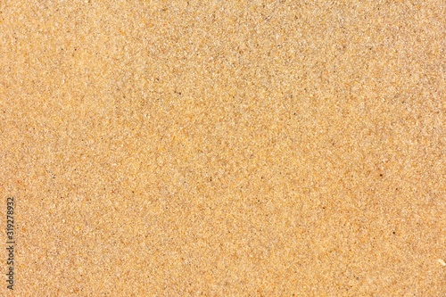 Golden sand background with selective focus. Textured yellow sand surface with soft focus. Summertime. Beach vacation. Seascape with clean sand. 