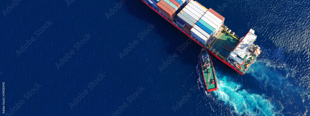 Fototapeta Aerial top down ultra wide photo of Container cargo Ship carrying load in truck-size colourful containers in deep blue open ocean sea