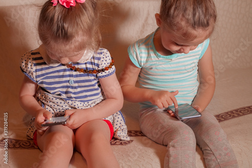 Bild auf Leinwand two small girls playing by phone at home