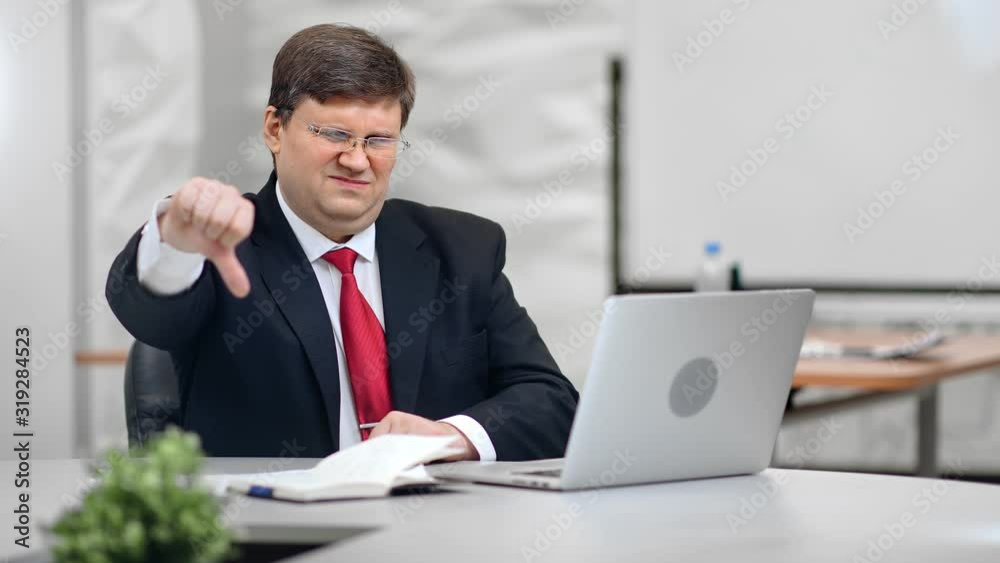 Portrait of disappointed male boss with unhappy expression showing thumb down Portrait of disappointed male boss with unhappy expression showing thumb down