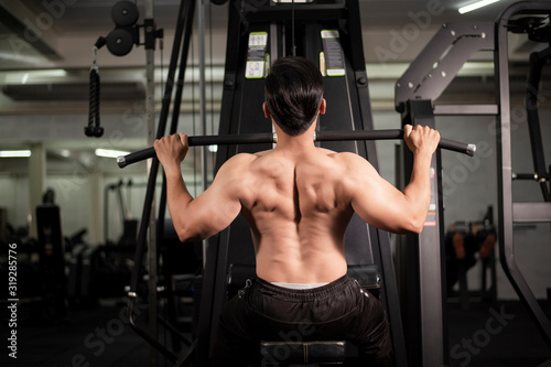 Bodybuilder man with big muscular back in the gym