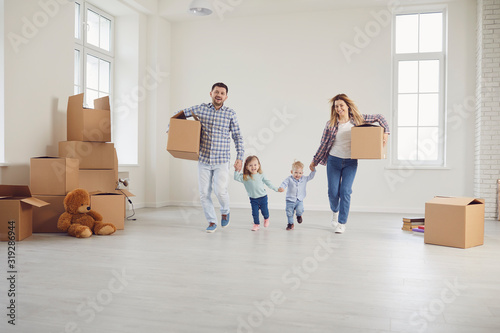 Happy family with children moving with boxes in a new apartment house.