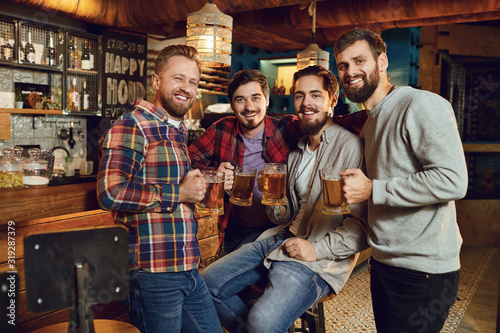 A group of friends is sitting in a bar with glasses of beer. © Studio Romantic