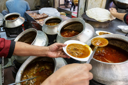 A restaurant worker spooning a mutton curry from the big pot at one of the restaurant in Chandni Chowk in Old Delhi India