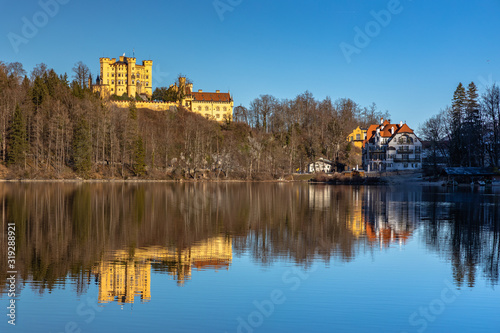 Stunning view of the Alpsee lake in winter on a sunny day with the Hohenschwangau Castle and Bavaria Alps in background, with beautiful reflections in water, Schwangau, Bavaria, Germany