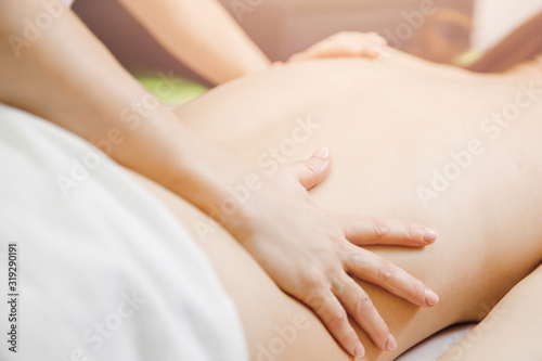 Young beautiful woman having professional back massage in spa salon