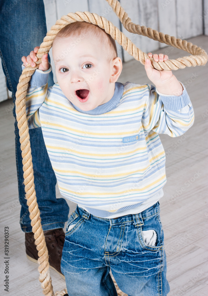 Little boy play with rope and smiles. Indoor photo shot