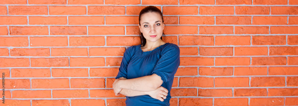Young beautiful woman stays in front of the red brick wall. Indoor photo shot. Empty space for your text Young beautiful woman stays in front of the red brick wall. Indoor photo shot. Empty space for your text