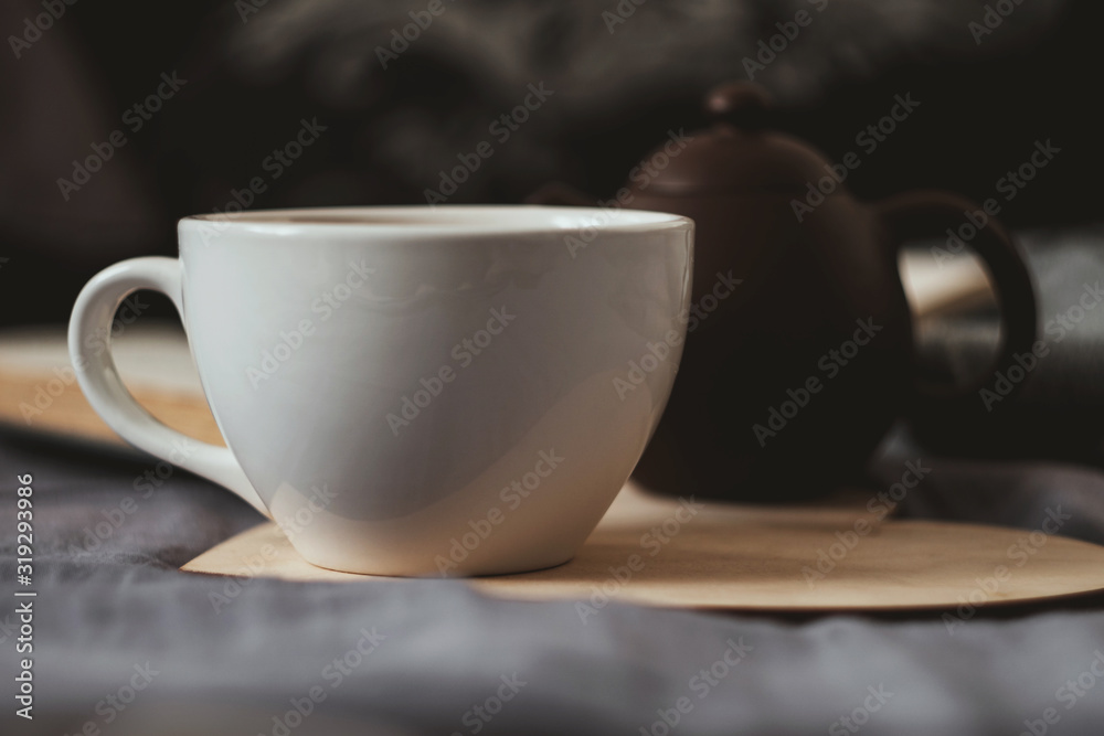Cup of tean and teapot on wooden heart book and scarf on background Cup of tean and teapot on wooden heart book and scarf on background