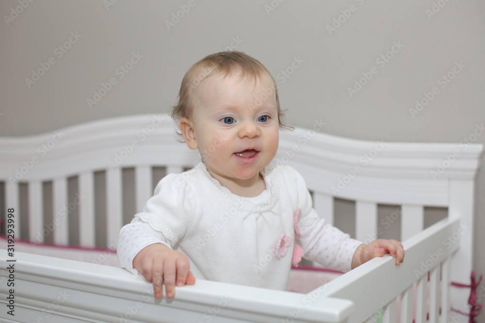 Very Cute 10 Month Old Baby Girl with Big Blue Eyes Playing in the White Crib Very Cute 10 Month Old Baby Girl with Big Blue Eyes Playing in the White Crib