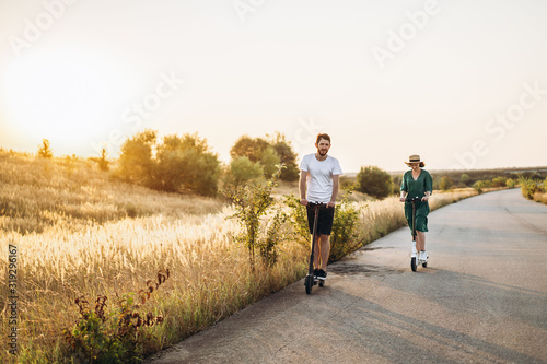Young couple on vacation having fun driving electric scooter on the road in the countryside. Content technologies. Copy space