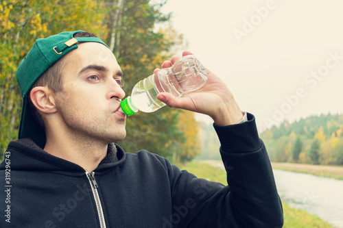 Concept of sports, training and active lifestyle. Young man quenches his thirst after a difficult workout