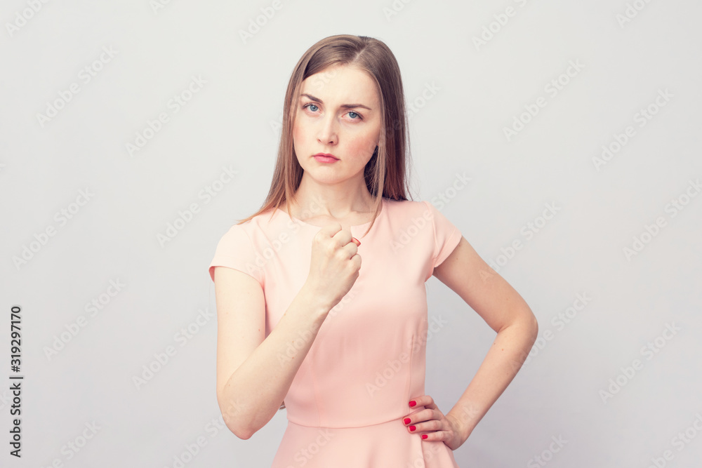 Angry woman threatening the first, grey background, portrait, toned Angry woman threatening the first, grey background, portrait, toned