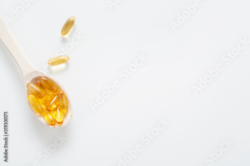 Fish oil capsules, in a wooden spoon, isolated on a white background, with copy space. Concept vitamins for skin and hair.