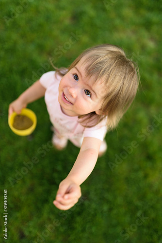 Baby girl portrait playing on green grass outdoors in sunny day. © Przemyslaw Iciak