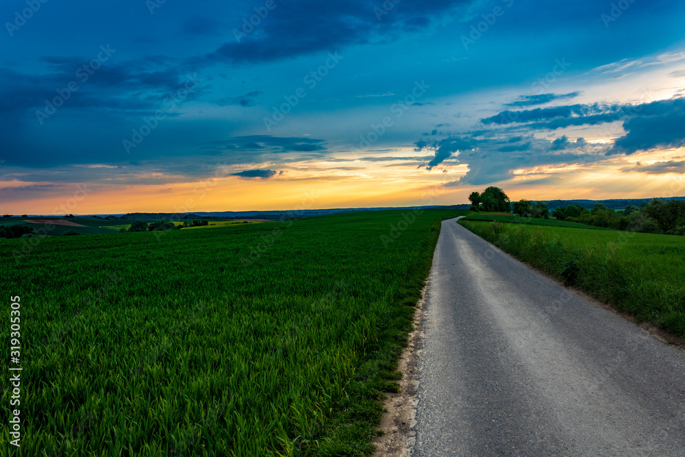 country road in the field against blue sunset sky in Neudenau, Germany. country road in the field against blue sunset sky in Neudenau, Germany.