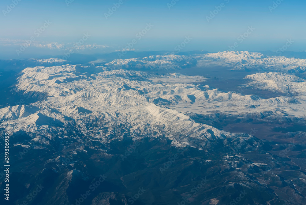 Winter mountains from the plane window. Turkish mountains landscape aerial view. Snow peaks.