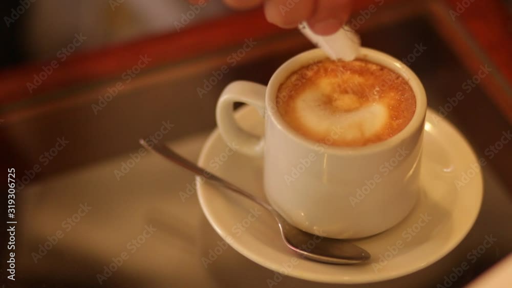  hand puts sugar inside the cafe on a wooden bar table