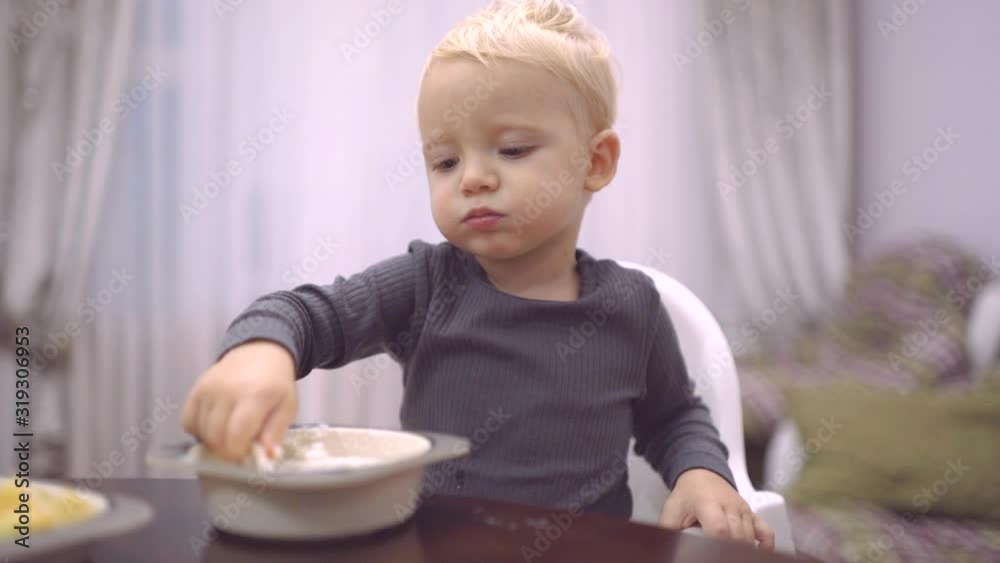 Food and Drink - Child eat concept. Little boy having breakfast in the kitchen. Happy baby boy spoon eats itself. Food and Drink - Child eat concept. Little boy having breakfast in the kitchen. Happy baby boy spoon eats itself.