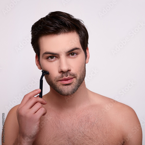 Concentrated brutal male with razor near beard