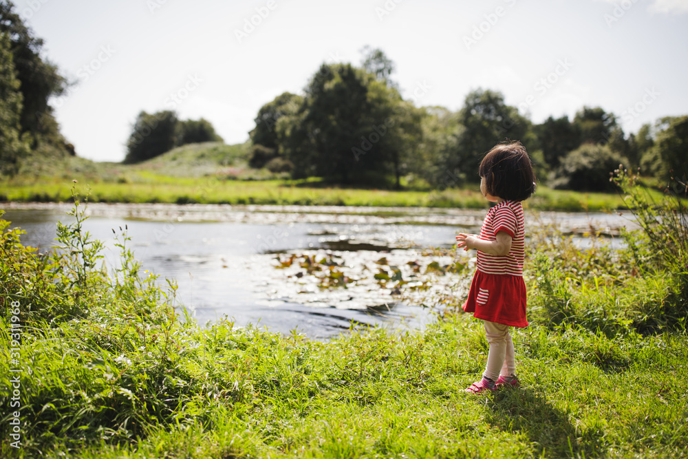 Φωτογραφία toddler girl playing in  summer countryside forest park,Northern Ireland