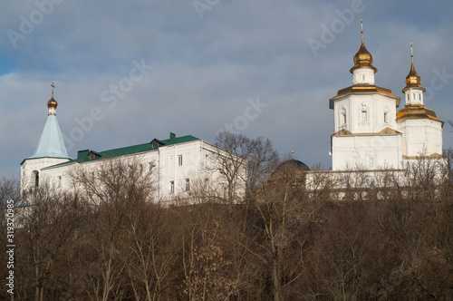 Church with golden domes on a background of trees and sky with clouds. photo