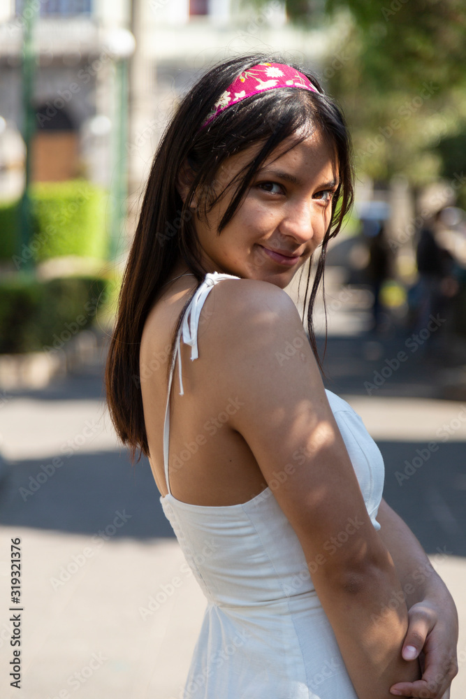 Hispanic woman portrait in the park smiling at the camera - woman with dress walking
