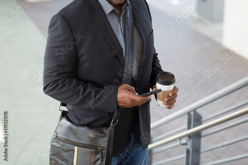 African American businessman drinking coffee and texting.