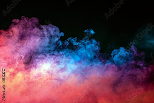 Abstract backlit smoke texture in red blue yellow on a black background.