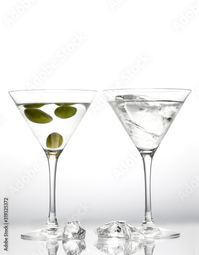 Martini glasses with green olives and pieces of melting ice