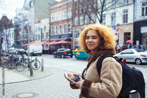 young pretty african american girl with curly hair making photo on a tablet, lifestyle people concept, tourist in european german city © iordani