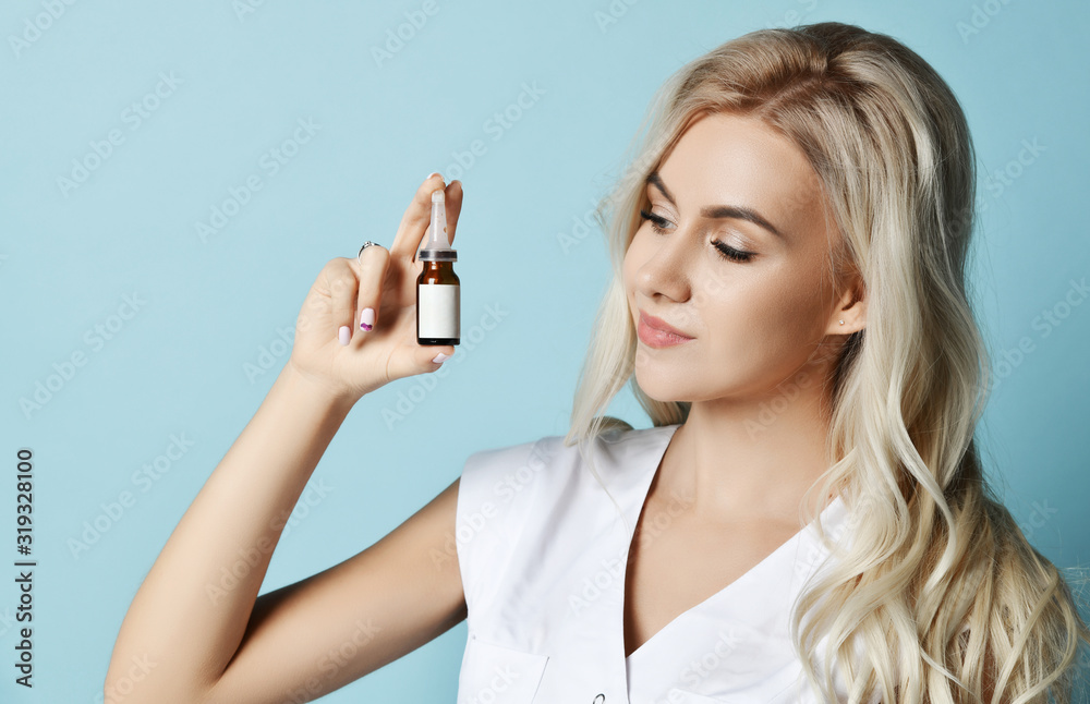 Portrait of young beautiful smiling sexy blond woman in white clothing holding small beauty ampoule in hands Portrait of young beautiful smiling sexy blond woman in white clothing holding small beauty ampoule in hands