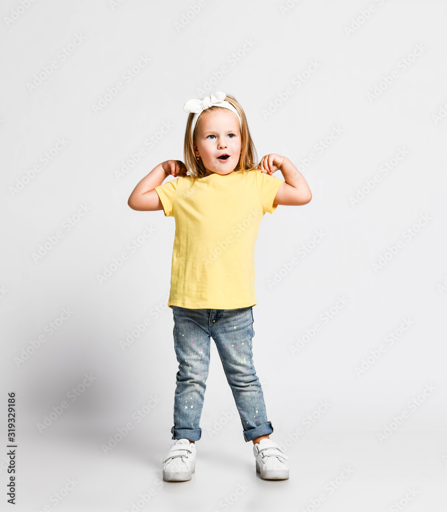 Active kid baby girl in yellow t-shirt is singing nursery rhyme dancing doing exercises with her hands on her shoulders Active kid baby girl in yellow t-shirt is singing nursery rhyme dancing doing exercises with her hands on her shoulders