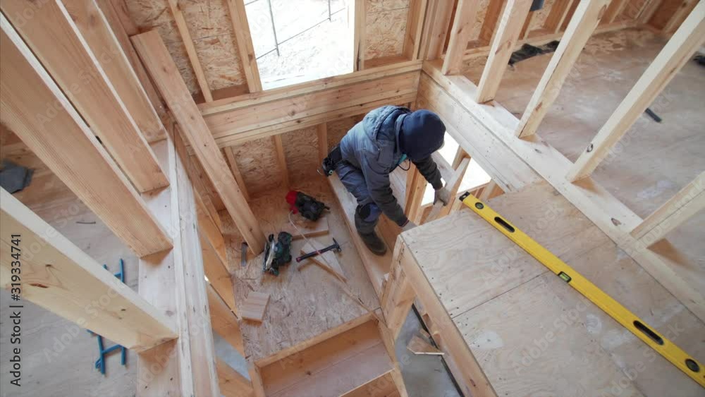 Top view of worker building ladder in wooden frame house Top view of worker building ladder in wooden frame house