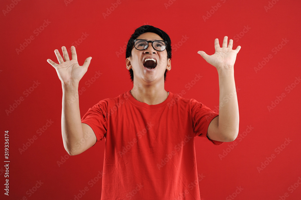 Naklejka premium Young asian man happy and excited expressing winning gesture. Successful and celebrating