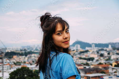 beautiful girl in a blue shirt smiling with city in the background