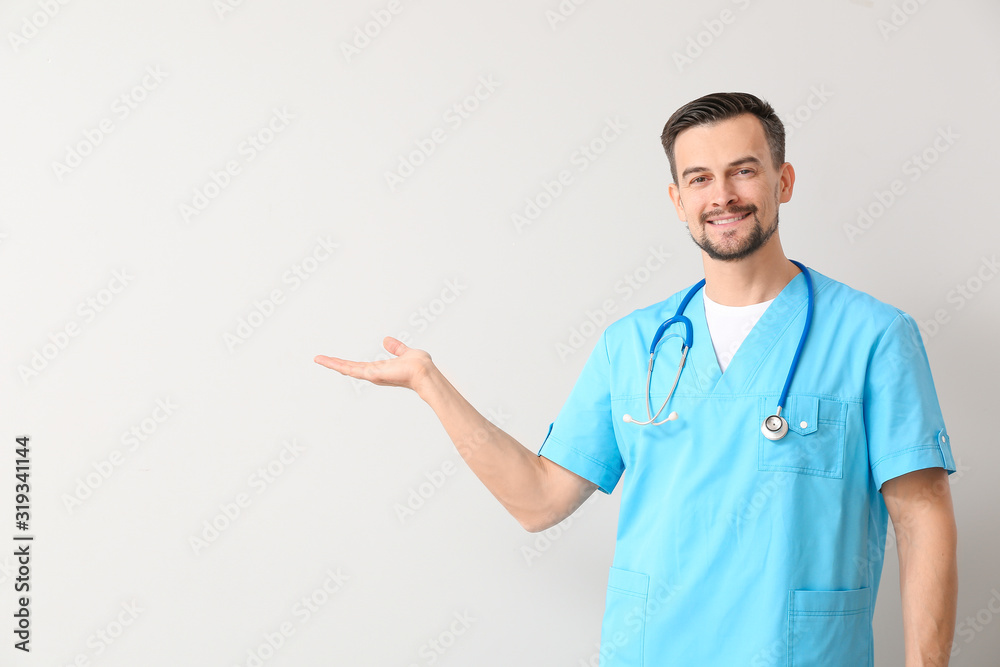 Portrait of male doctor showing something on light background Portrait of male doctor showing something on light background