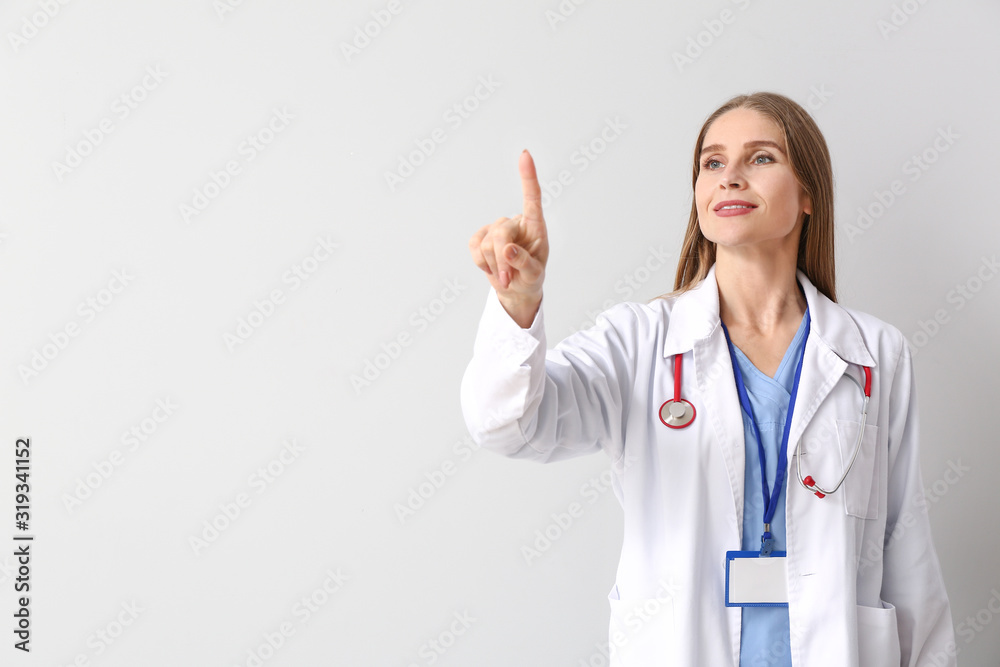 Portrait of female doctor showing something on light background Portrait of female doctor showing something on light background