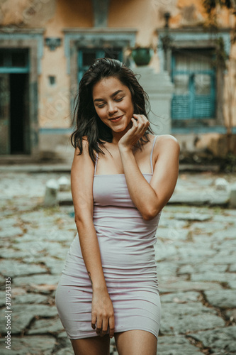 beautiful and sensual girl smiling in pink dress in front of an old house