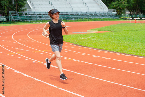 Portrait of young happiness athlete runner woman running in the running track in stadium. Running track is a rubberized artificial running surface for track and field athletics.