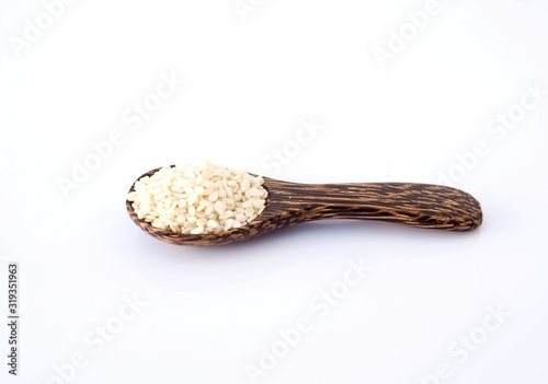 Cereal dried food whole grains with white sesame seeds in wooden spoon isolated on white background.