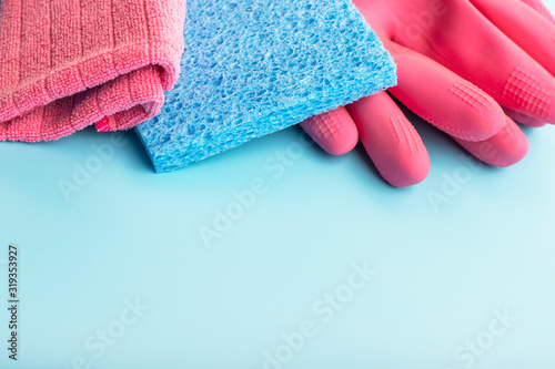 Rag and pink gloves on blue background with copy space, concept spring cleaning