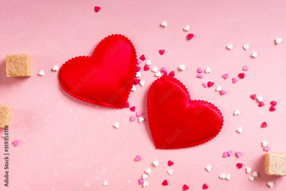Red fabric hearts, sugar cubes, confetti on pink background. Valentines day 14 february love minimal concept