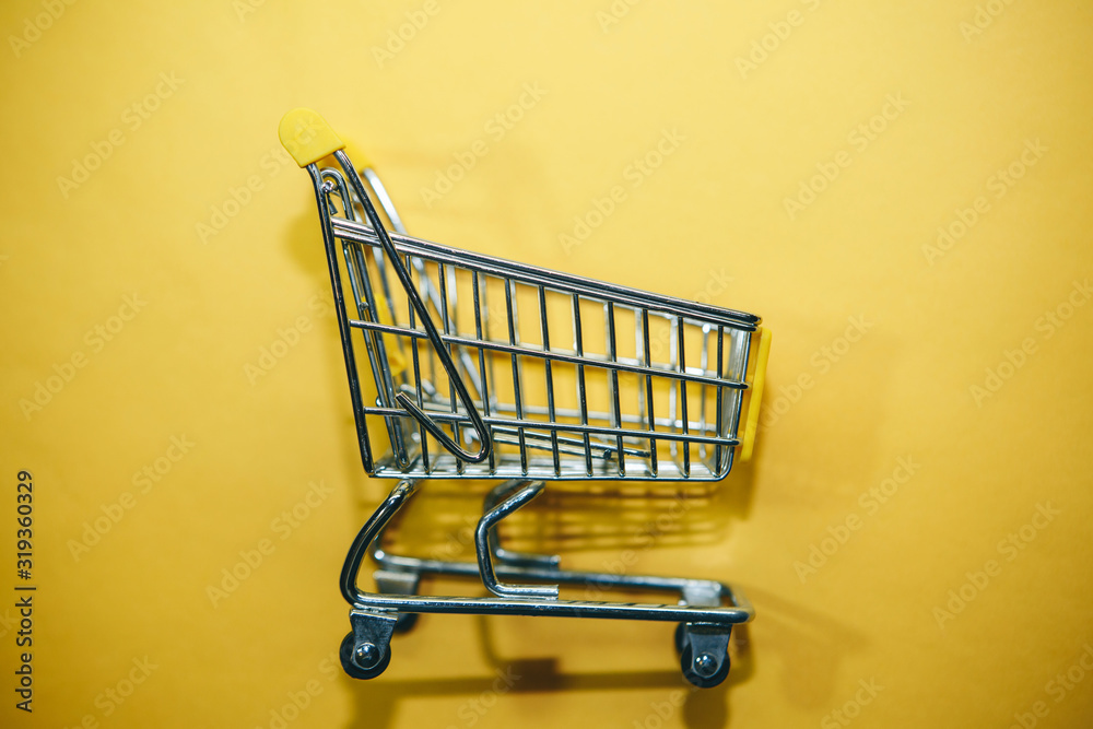 Shopping cart on a trendy yellow background in a minimal style. Shopping cart on a trendy yellow background in a minimal style.