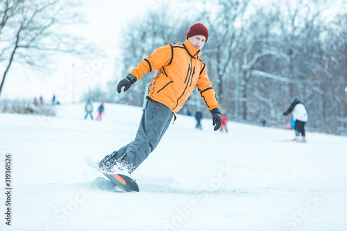 young man riding snowboard by winter hill