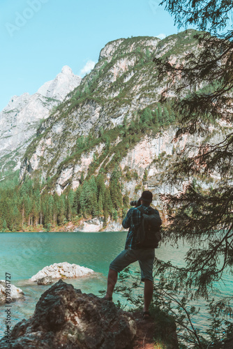man climbing by rocks to shoot beautiful landscape of lake and mountains